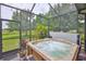 Relaxing hot tub enclosed in a screened patio, offering privacy and protection from the elements, overlooking lush backyard at 6516 Salt Creek Ave, Apollo Beach, FL 33572