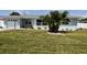 Charming home with a manicured lawn, mature palm tree, white rock landscaping, and decorative white window shutters at 123 9Th St, Belleair Beach, FL 33786
