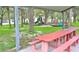 Community playground features swings, slide, and a picnic table under the shade of beautiful trees at 123 9Th St, Belleair Beach, FL 33786
