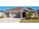 Charming single-story home featuring a two-car garage, stone accents, and a well-maintained lawn at 17671 Bright Wheat Dr, Lithia, FL 33547