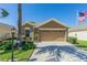 Exterior view of a home with an attached two-car garage, American flag, and neatly trimmed landscaping at 18829 Water Lily Ln, Hudson, FL 34667