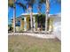 Charming yellow home featuring a spacious driveway and well-manicured lawn with palm trees, creating a welcoming curb appeal at 3447 Loveland Blvd, Port Charlotte, FL 33980