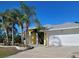 Charming yellow home featuring a spacious driveway and well-manicured lawn with palm trees, creating a welcoming curb appeal at 3447 Loveland Blvd, Port Charlotte, FL 33980