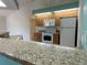 Kitchen with a breakfast bar featuring stone countertops, wooden cabinets, and white appliances at 3447 Loveland Blvd, Port Charlotte, FL 33980