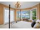 Bedroom with four poster bed, bay windows with lake views and decorative chandelier at 11710 N Armenia Ave, Tampa, FL 33612