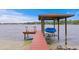 Covered boat dock featuring a boat lift, a seating area, and views of the lake at 11710 N Armenia Ave, Tampa, FL 33612