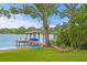 Beautiful waterfront home featuring a dock with boat lift, seating area, and lush landscaping at 11710 N Armenia Ave, Tampa, FL 33612