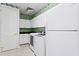 Laundry area with white cabinets, modern washer and dryer, and green wallpaper at 11710 N Armenia Ave, Tampa, FL 33612