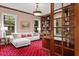 An executive office with a white couch, red carpet, wood paneling, and glass paneled doors to the foyer at 11710 N Armenia Ave, Tampa, FL 33612