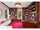Office with custom, dark wood built-in shelving, red carpet, and natural light from the large windows at 11710 N Armenia Ave, Tampa, FL 33612