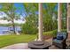 Covered patio featuring waterfront and dock views with manicured lawn and decorative pillow at 11710 N Armenia Ave, Tampa, FL 33612