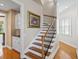 Elegant staircase with wooden steps, iron railing and bright natural light, alongside a decorative fruit artwork at 11710 N Armenia Ave, Tampa, FL 33612