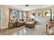 Inviting living room featuring a comfortable brown leather sectional sofa, bright windows, and stylish decor at 4235 Moody St, St Pete Beach, FL 33706