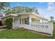 A well-maintained home featuring a white exterior, blue shutters, and a quaint front yard with lush green grass at 51 Lexington Dr, Dunedin, FL 34698