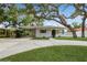 Charming single-story home with a well-maintained lawn and mature trees providing ample shade at 51 Lexington Dr, Dunedin, FL 34698