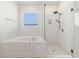 Well-lit bathroom with a tub, shower, and white marble tile, perfect for a relaxing and refreshing experience at 6232 Sea Air Dr, Apollo Beach, FL 33572