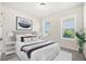 Bright bedroom with a queen bed, decorative pillows, and large windows offering views of the landscaped surroundings at 6232 Sea Air Dr, Apollo Beach, FL 33572