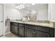 Bathroom with a double vanity, granite countertops, dark cabinetry, and large mirror at 10374 Echo Dock Loop, San Antonio, FL 33576