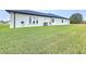 Backyard featuring a large green lawn with the side of the stucco home with arched windows at 11199 Warm Wind Way, Weeki Wachee, FL 34613