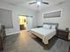 Bedroom with gray and white bedding, a ceiling fan and a sliding barn door to a bathroom at 11199 Warm Wind Way, Weeki Wachee, FL 34613