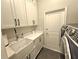 Laundry room with white cabinets, quartz counters, farmhouse sink, and modern washer/dryer at 11199 Warm Wind Way, Weeki Wachee, FL 34613