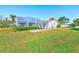 Expansive backyard featuring a screened-in lanai, well-maintained lawn, and mature landscaping at 1575 Brookside Blvd, Largo, FL 33770