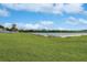 A well-manicured lawn extends to a serene lake, framed by a beautiful blue sky at 814 Fern Leaf Dr, Ruskin, FL 33570