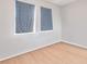 Bedroom with wood-look flooring, neutral paint and two windows with patterned curtains, offering a comfortable retreat at 814 Fern Leaf Dr, Ruskin, FL 33570