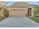 Beige two car garage door with manicured green grass alongside a concrete driveway at 814 Fern Leaf Dr, Ruskin, FL 33570