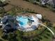 Aerial view of a community pool with a slide and plenty of lounge chairs surrounded by a grassy area at 30160 Skylark Dr, Wesley Chapel, FL 33545