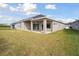 Expansive backyard with lush green grass and neutral home exterior with covered patio for entertaining at 6123 Hidden Branch Dr, Apollo Beach, FL 33572