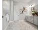 Elegant bathroom with marble floors, gray vanity, framed artwork, and a separate door to the tiled shower at 6123 Hidden Branch Dr, Apollo Beach, FL 33572