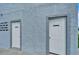 Exterior image of two white doors set into the gray textured exterior of a building at 18325 Gulf Blvd # 407, Redington Shores, FL 33708
