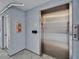 Hallway view with an elevator and a fire extinguisher mounted near a door at 18325 Gulf Blvd # 407, Redington Shores, FL 33708