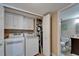 Laundry room with washer, dryer, storage cabinets and an open door to an attached bathroom at 18325 Gulf Blvd # 407, Redington Shores, FL 33708