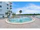 Community pool and seating area with palm trees next to a building under a clear blue sky at 18325 Gulf Blvd # 407, Redington Shores, FL 33708