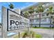 Sign reads, Portside Condominiums, with building in background, with palm trees under a blue sky at 18325 Gulf Blvd # 407, Redington Shores, FL 33708