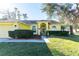 Inviting one-story home featuring a vibrant yellow exterior, lush landscaping, and a welcoming arched entryway at 5215 New Brittany Ln, Zephyrhills, FL 33541