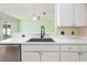 Close-up of the kitchen sink area with white cabinets and a view to the living room at 5215 New Brittany Ln, Zephyrhills, FL 33541