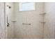 Close up of marble-look shower featuring a safety bar, hand shower, overhead shower, and corner shelving at 5215 New Brittany Ln, Zephyrhills, FL 33541