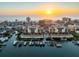 Stunning aerial view of waterfront condos with boat docks and a beautiful sunset over the ocean at 5301 Gulf Blvd # E202, St Pete Beach, FL 33706