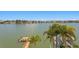Expansive waterfront view highlighting a wooden dock with boat lift and lush palm trees along the calm canal waters at 17059 Dolphin Dr, North Redington Beach, FL 33708