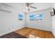 Bedroom featuring hardwood floors, two windows, a ceiling fan and an AC unit for comfort at 8716 Hickorywood Ln, Tampa, FL 33615