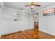 Bedroom featuring hardwood floors, closet, ceiling fan, built-in shelving, with a doorway to the hallway at 8716 Hickorywood Ln, Tampa, FL 33615