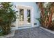 Elegant entrance featuring glass double doors, framed by tropical foliage and a beautifully paved walkway at 8750 Harrell Ave, Treasure Island, FL 33706
