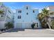Stunning three-story home with two-car garage, showcasing a well-manicured front yard and inviting entrance at 8750 Harrell Ave, Treasure Island, FL 33706