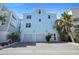 Stunning three-story coastal home boasts a two-car garage, lush landscaping, and modern design at 8750 Harrell Ave, Treasure Island, FL 33706