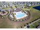 Aerial view of a modern community featuring a pool, lounge chairs and lush landscaping at 16719 Delia St, Wimauma, FL 33598