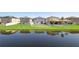 Backyard pond view with lush green grass and modern homes in the background at 16719 Delia St, Wimauma, FL 33598