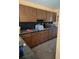 Functional kitchen area with wood cabinets, microwave, and contrasting black backsplash and countertop at 2280 Toniwood Ln, Palm Harbor, FL 34685
